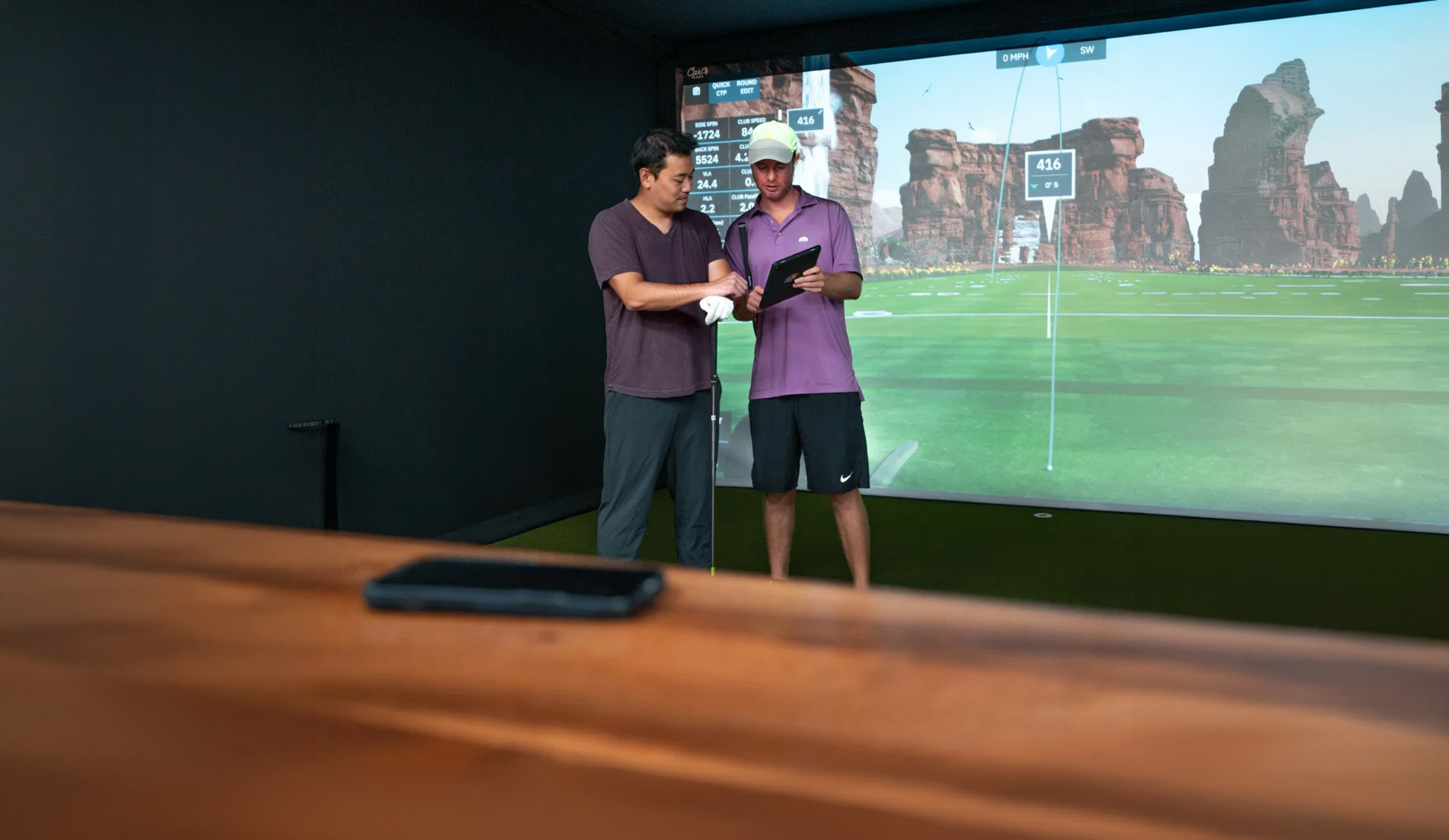Mark Odenthal reviewing swing data with a student in a golf simulator bay